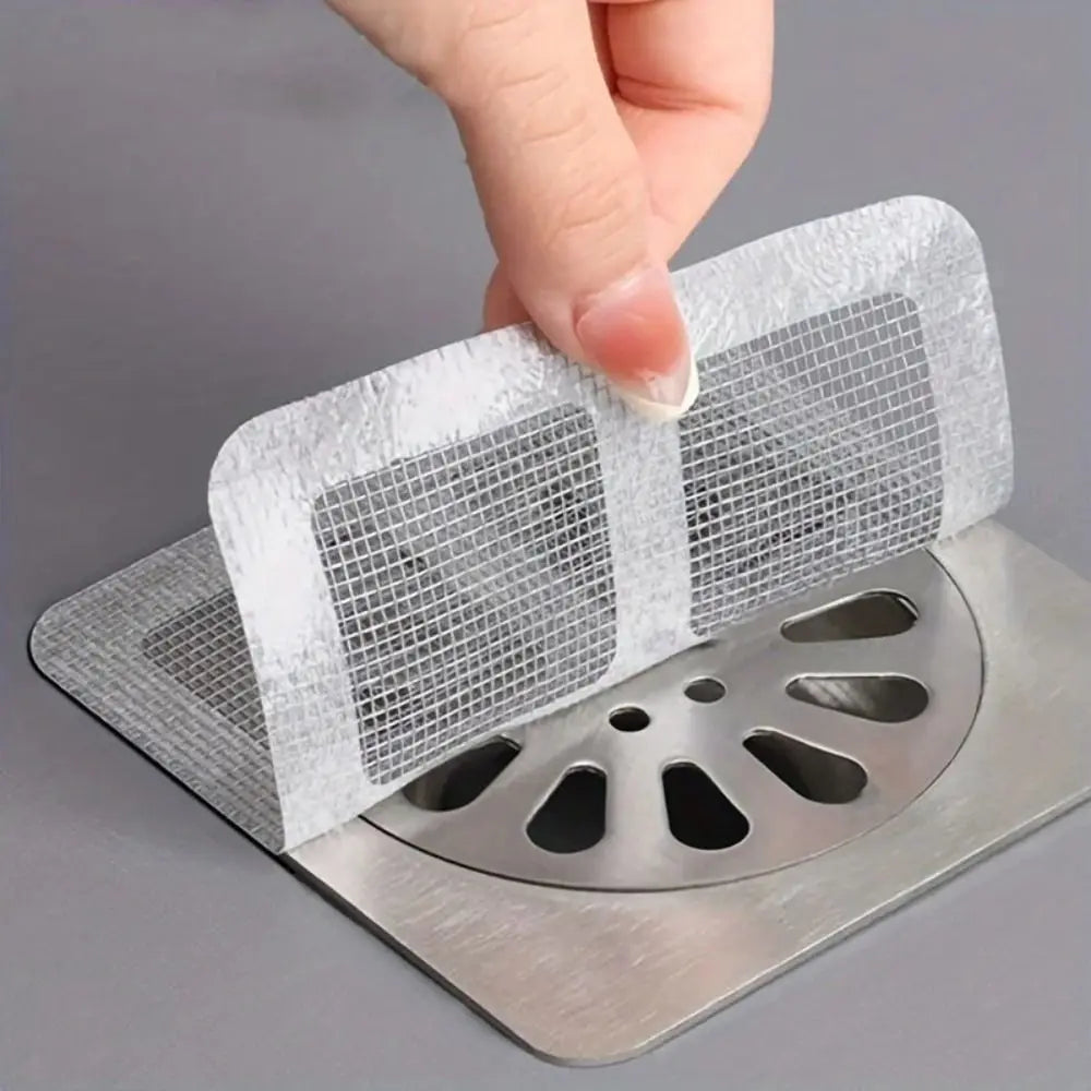 Eine Hand legt ein Einweg-Abflussfilter-Etikett auf ein Metallabflussgitter.