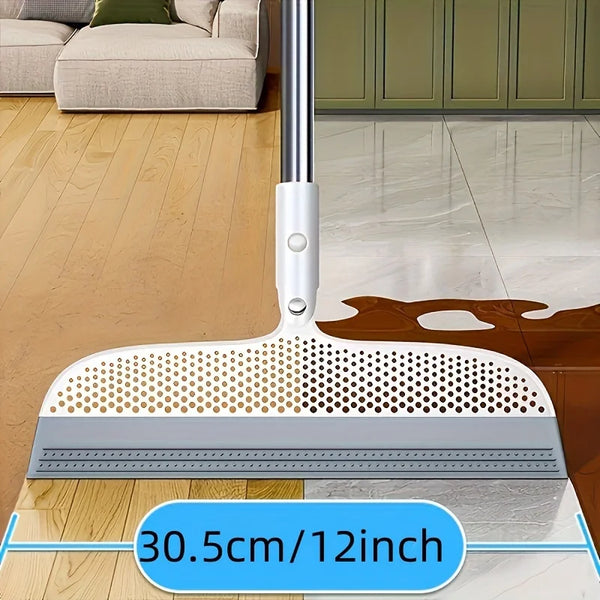 A silver ergonomic broom and scraper set with a wide head is shown on a wooden floor.