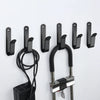 A set of heavy duty black iron wall mount hooks with attached cables and mounting hardware.