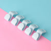 A row of white plastic clothes hanger hooks arranged diagonally on a pink and blue background.