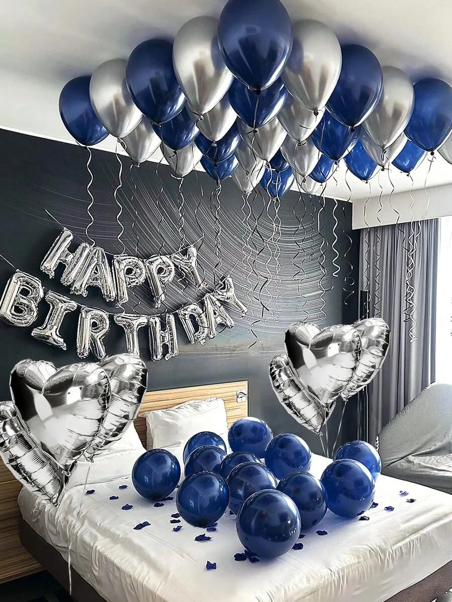 A silver and blue foil balloon garland decorating a room, with balloons on a white table.