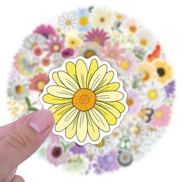 A hand holds a yellow daisy flower decal against a background of colorful floral patterns.