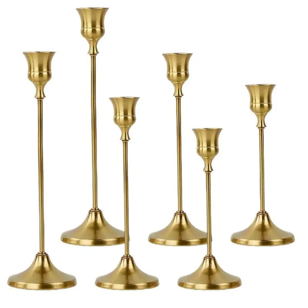 A set of three elegant brass metal candle holders with tapered bases and slender stems.