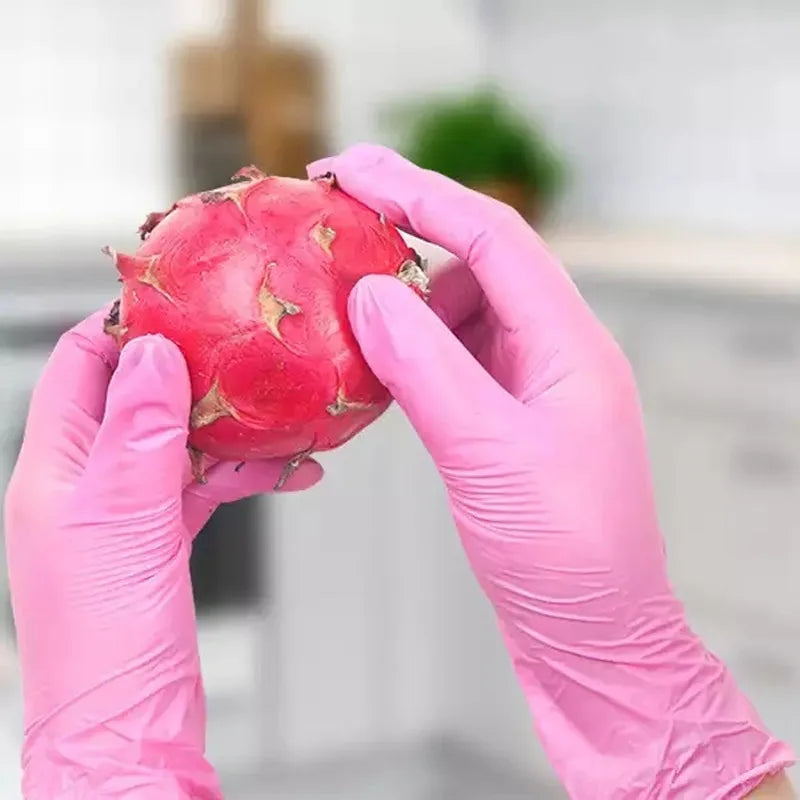 A hand wearing pink nitrile gloves is holding a bright red, textured fruit.