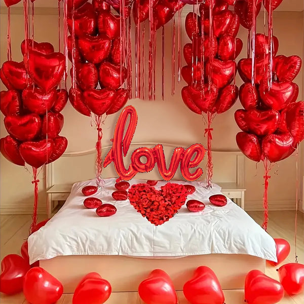Eine Anordnung roter herzförmiger Ballons und eines großen roten Herzschilds um ein Bett.