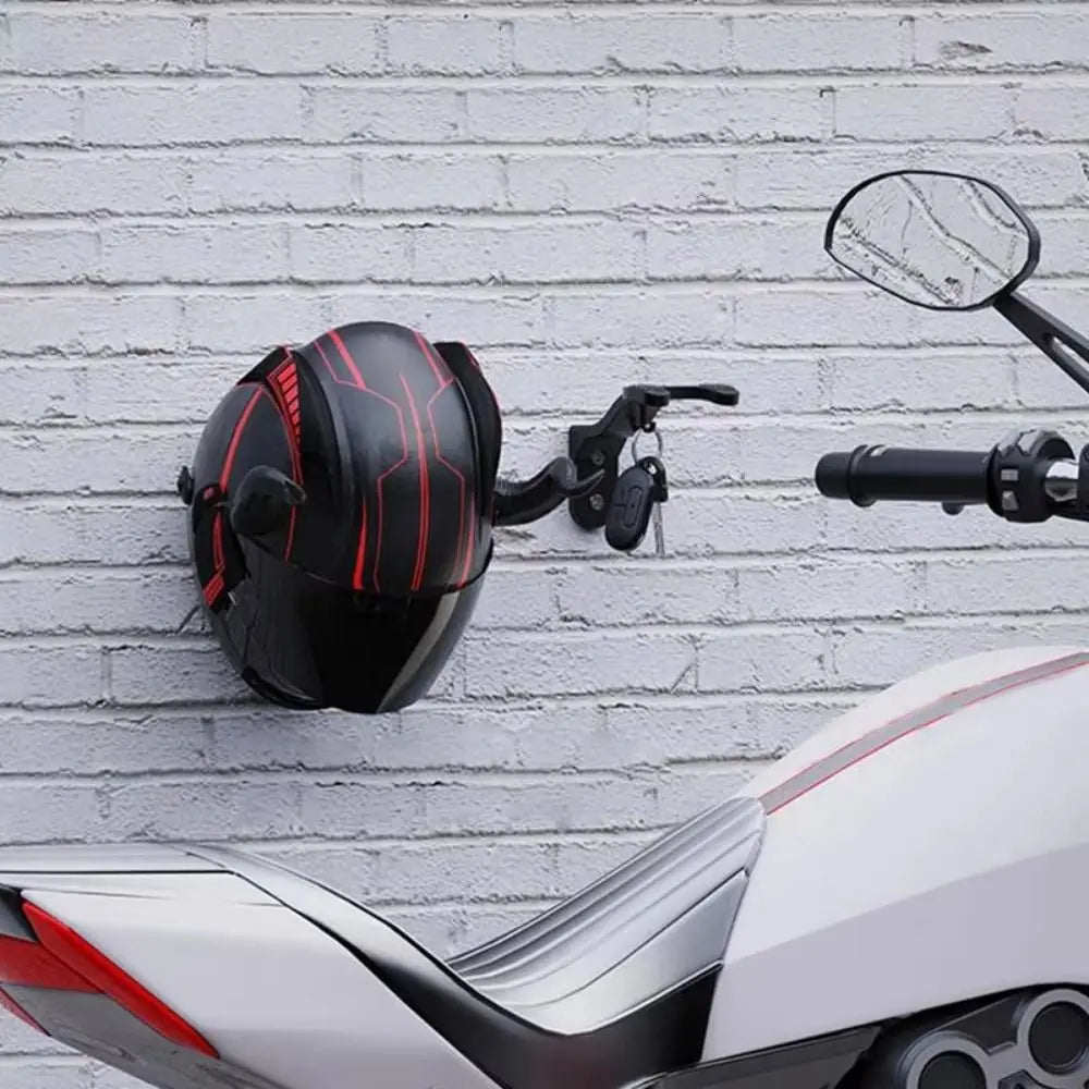 Black and red wall hooks mounted on a white brick wall above a silver motorcycle bodywork.