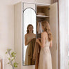 A woman stands in front of a full body wall mirror with an aluminum frame, looking at her reflection.