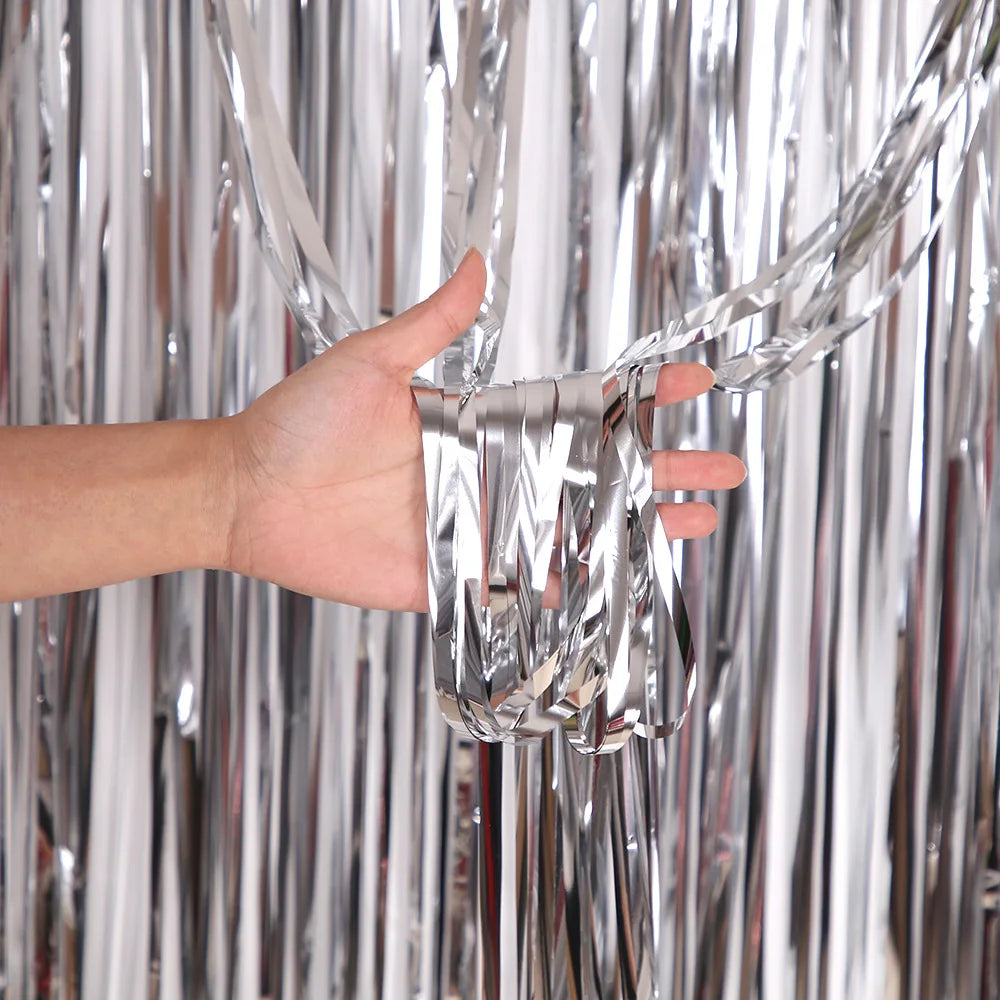 Eine Hand hält und manipuliert silberne, metallische Tinselfolienvorhänge.