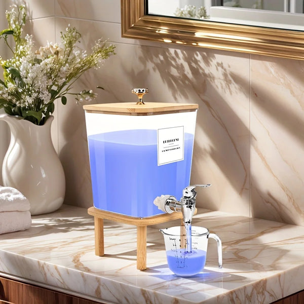 A stainless steel laundry detergent dispenser with a wooden stand and blue liquid, placed on a marble countertop.