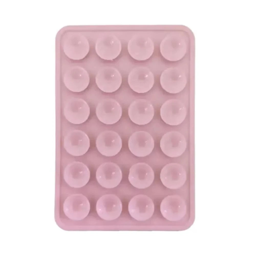 A pink silicone suction cup phone stand with multiple circular holes for hands-free viewing.