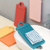 A collection of colorful portable anti-slip wash basins in orange, pink, and teal resting on a white ceramic basin.