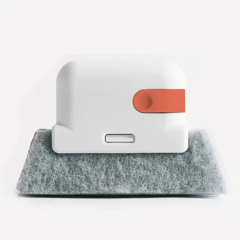 A white cleaning brush with an orange section rests on a gray felt surface.