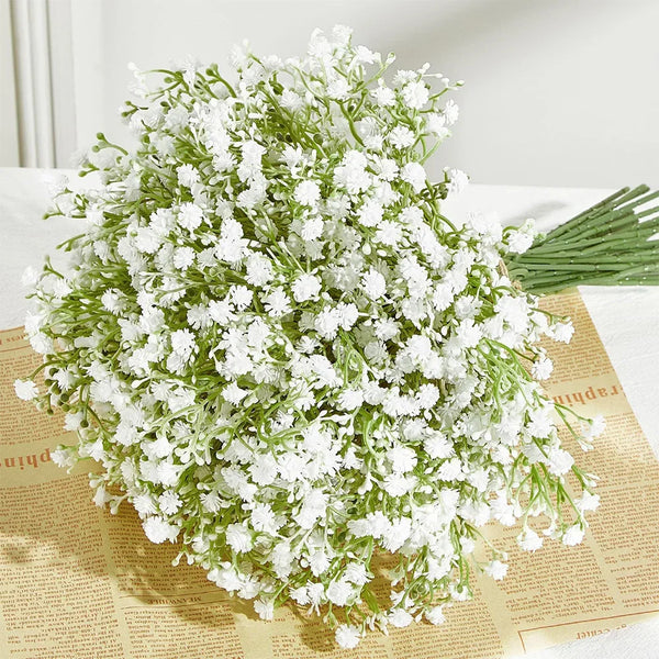 A bouquet of artificial baby's breath flowers with green stems displayed on aged paper.