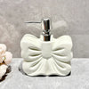 A white ceramic pump dispenser bottle with a bowknot design and a silver pump top.
