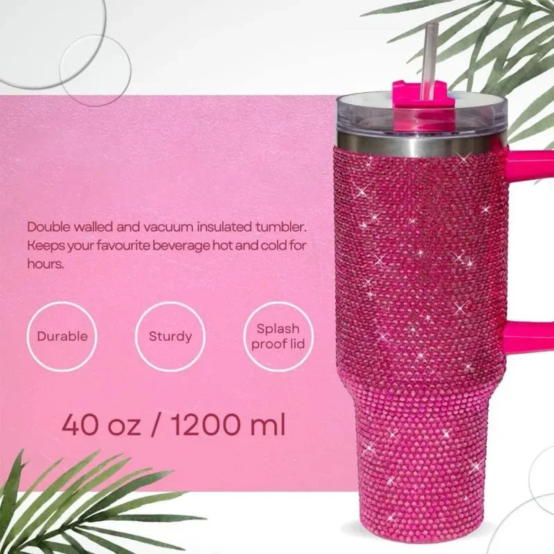 Taza aislada de acero inoxidable con pedrería rosa y tapa transparente y pajita rosa, sobre fondo claro.