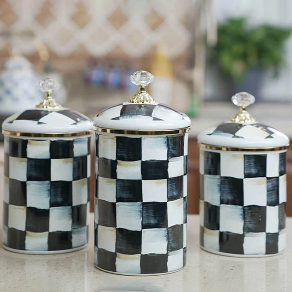 A set of three retro enamel storage jars with black and white checkered patterns and gold lids.