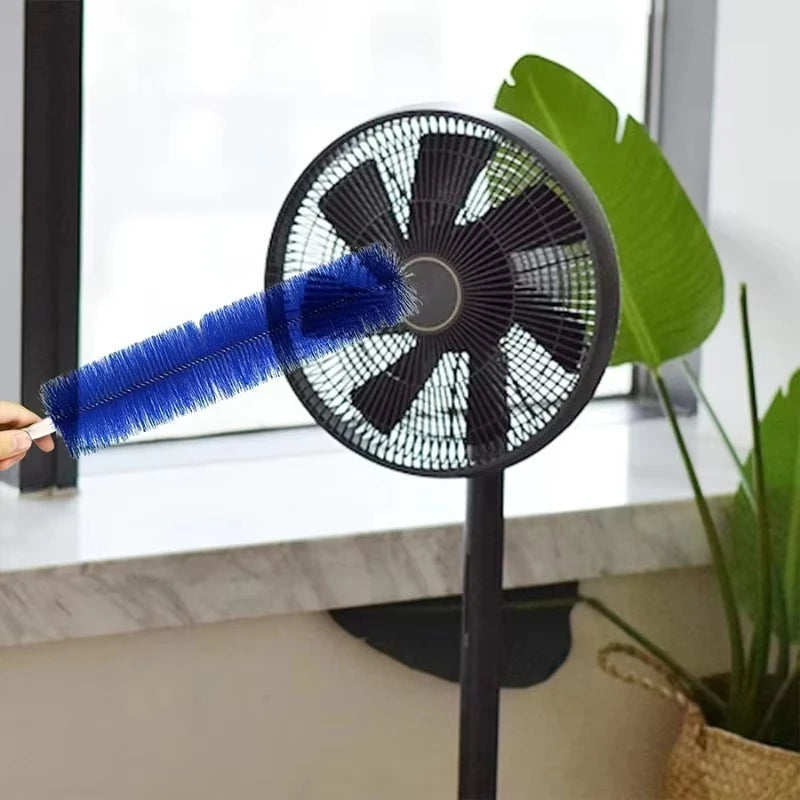 A blue cleaning brush is shown being used on a black electric fan for blind cleaning.