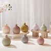 A collection of round silicone candle molds in various muted pastel and natural tones displayed on a white surface.