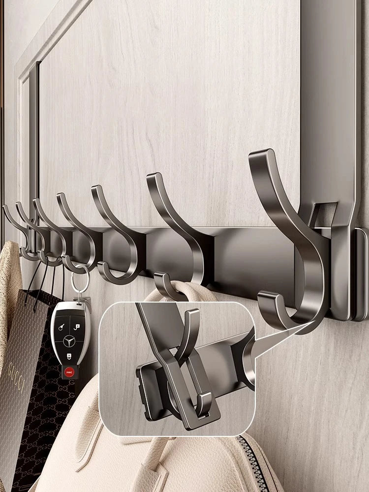 A close-up of a dark gray over-the-door organizer rack with extended arms mounted on a light wood cabinet door.