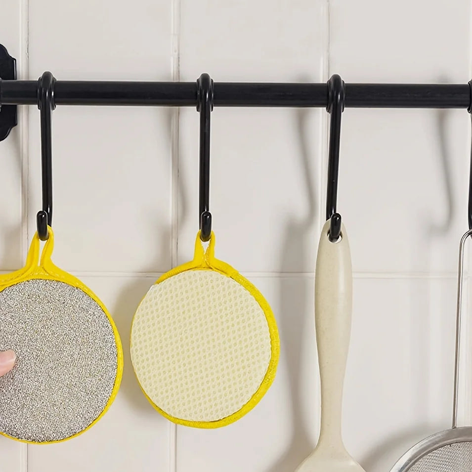 A set of yellow and white reusable double-sided dishwashing sponges hanging on a black bar.