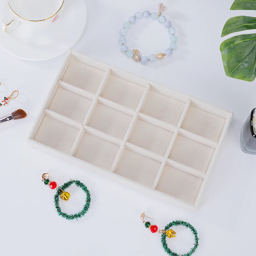 A light wood jewelry organizer tray with multiple compartments and several beaded bracelets are displayed on a white surface.