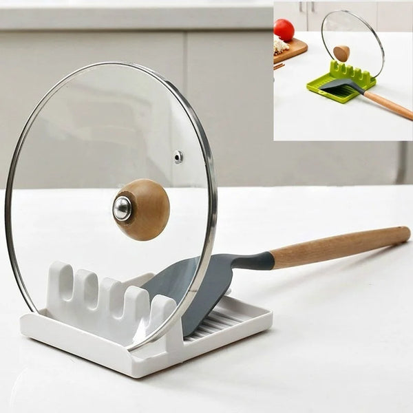 A clear glass utensil holder with a wooden spoon rest and a silicone spatula visible on a white table.