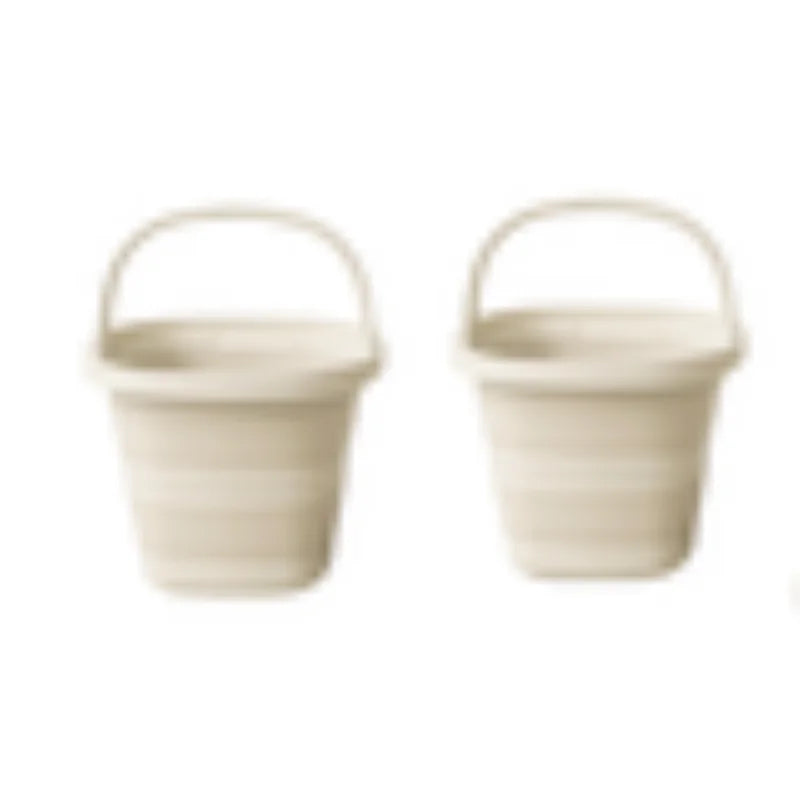 A pair of light beige collapsible water buckets with handles shown side by side.