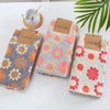 A set of three textured kitchen cleaning cloths in floral patterns with natural jute tags.
