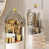 A clear, spherical makeup brush organizer with a lid displaying various cosmetic brushes and pencils.