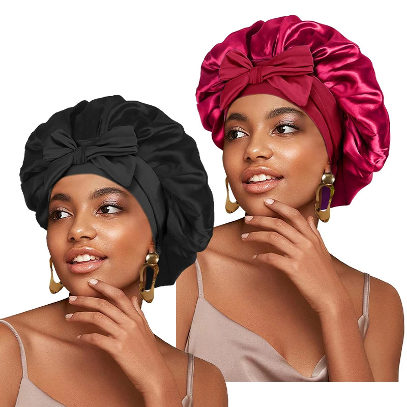 A woman models a satin sleeping cap in deep pink and black, featuring an adjustable tie band.