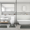 Ein modernes weißes Badezimmer mit Toilette, Waschbereich und Badewanne mit drei dunkelgrauen Memory-Schaum-Matten.