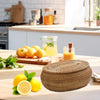 Handwoven rattan storage basket with lid filled with fresh lemon juice and slices on a wooden table.