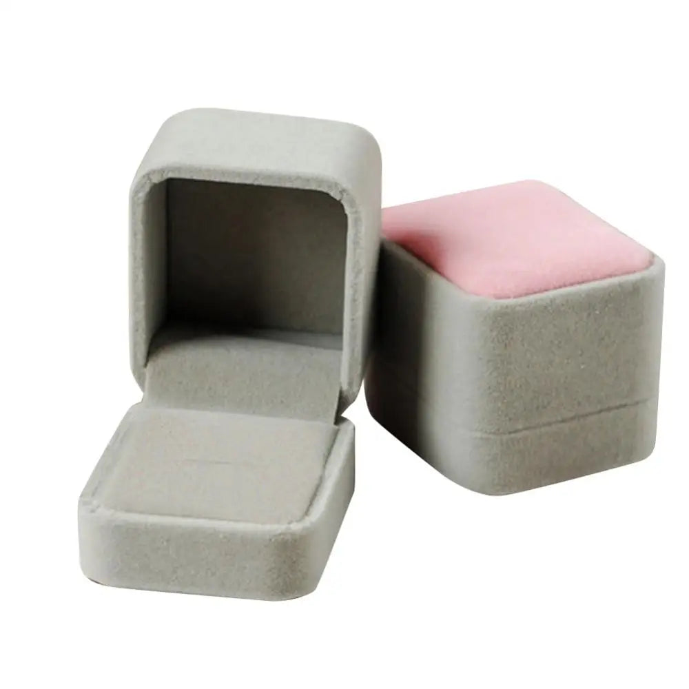 A light gray velvet jewelry box with a hinged lid, showing a pink velvet insert.