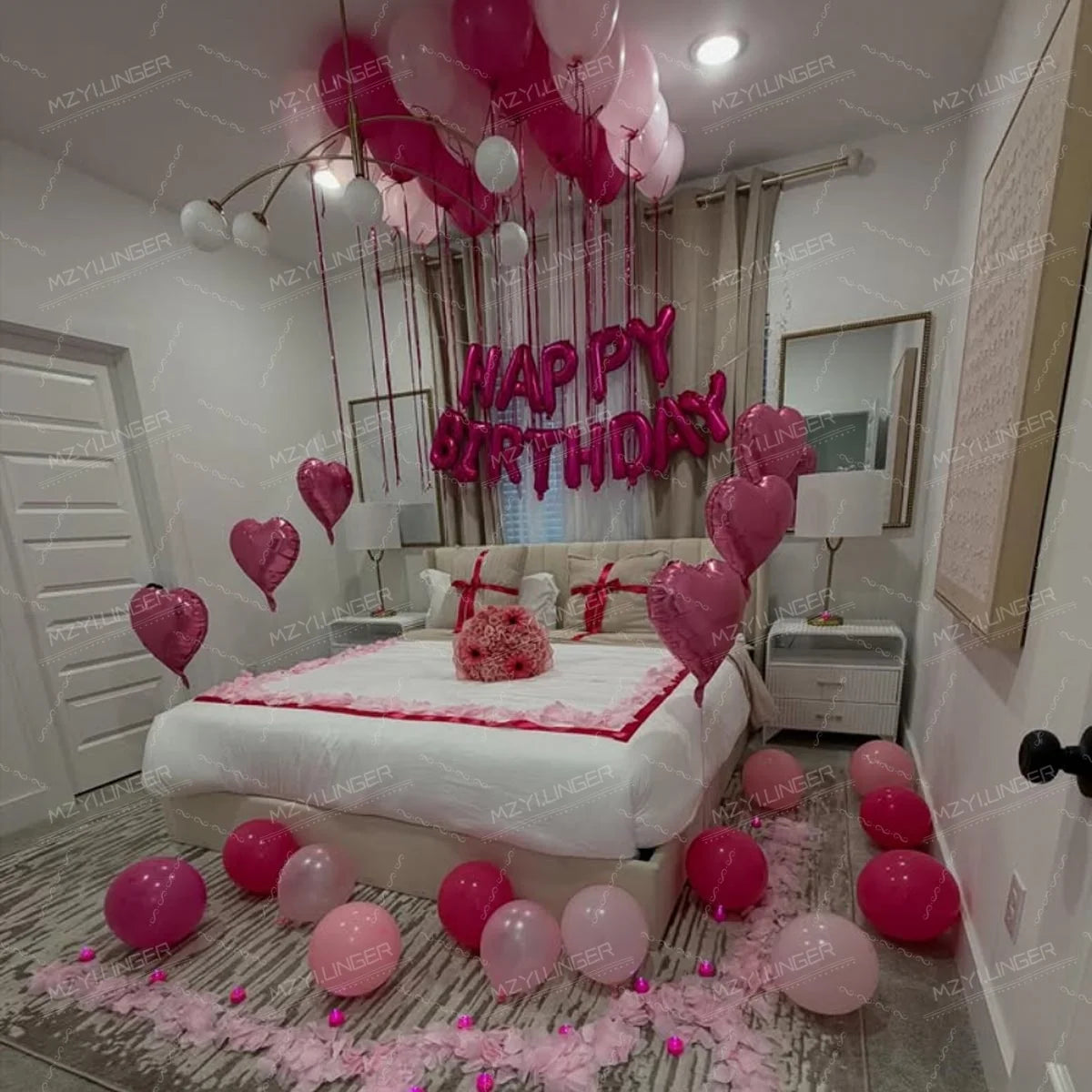 A pink heart birthday balloon set decorated with pink and white balloons on a bed.