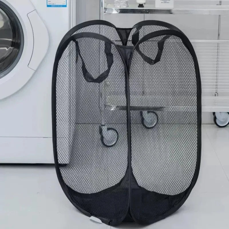 Black foldable mesh laundry basket organizer with two compartments placed next to a white washing machine.
