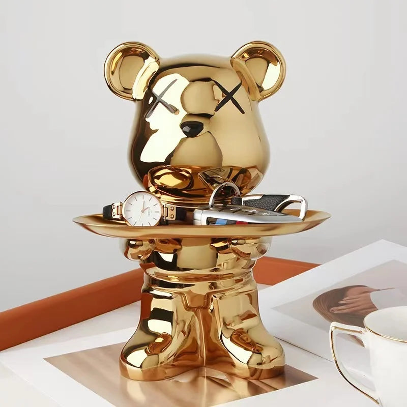 A shiny gold French bulldog sculpture holding a coin bank and snack holder.