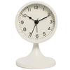 A white round analog alarm clock with black hands and a white base.
