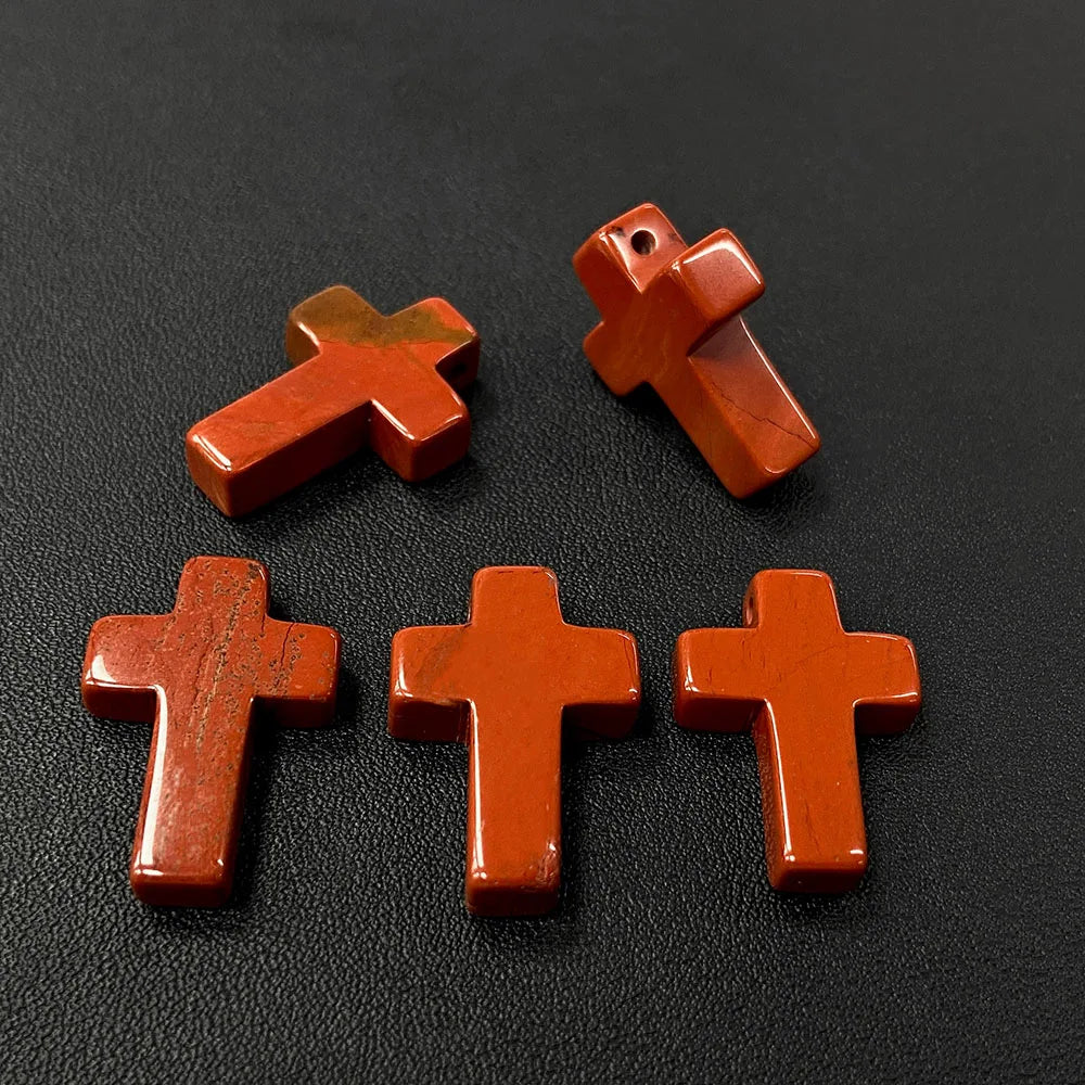 Three wooden cross pendant charms made of natural agate and jasper resting on a dark surface.