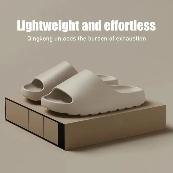 A pair of light beige Cloud Comfort EVA slides resting on a wooden block.