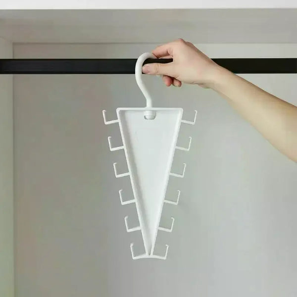 A hand is hanging a white multi-hook closet organizer hanger onto a black rod in a room.