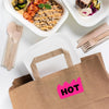A brown paper bag with a fluorescent pink sticker labeled HOT, next to wooden cutlery and food
