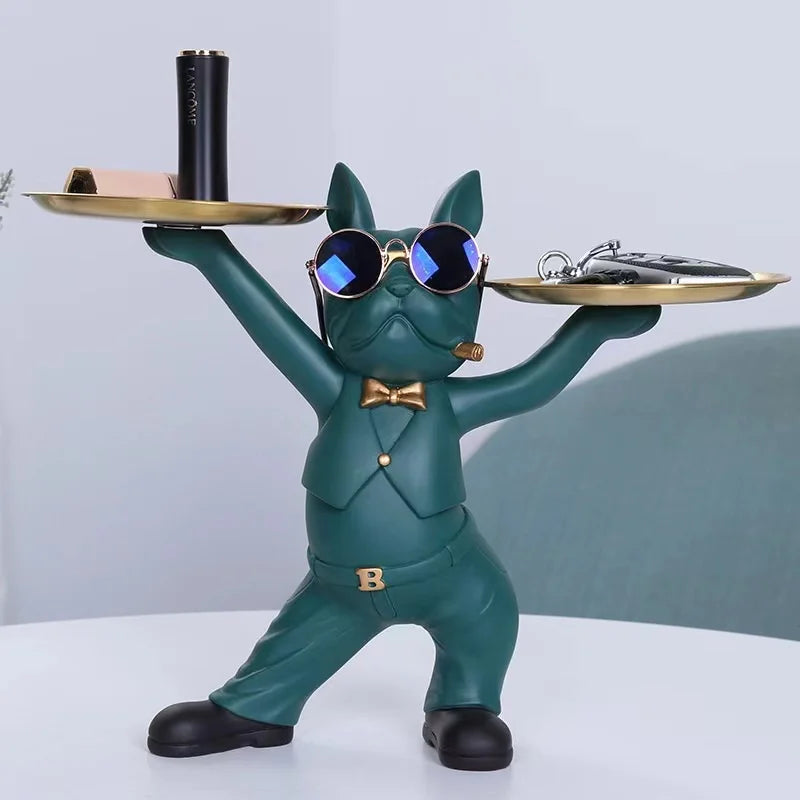 A green French bulldog sculpture holding a coin bank and a snack holder on its paws.