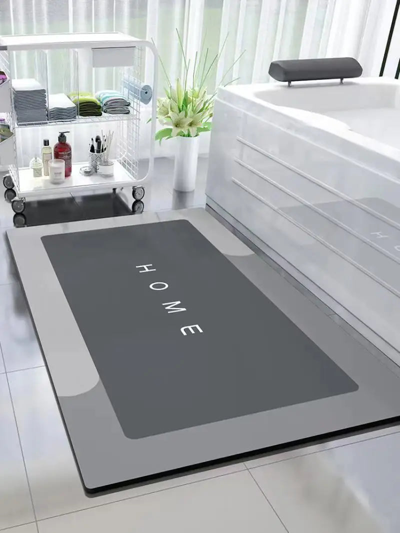A modern gray anti-slip floor mat is displayed next to a white bathroom sink and a glass storage shelf.