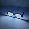 A pair of black LED light up anime glasses resting on a surface, casting a bright glow.