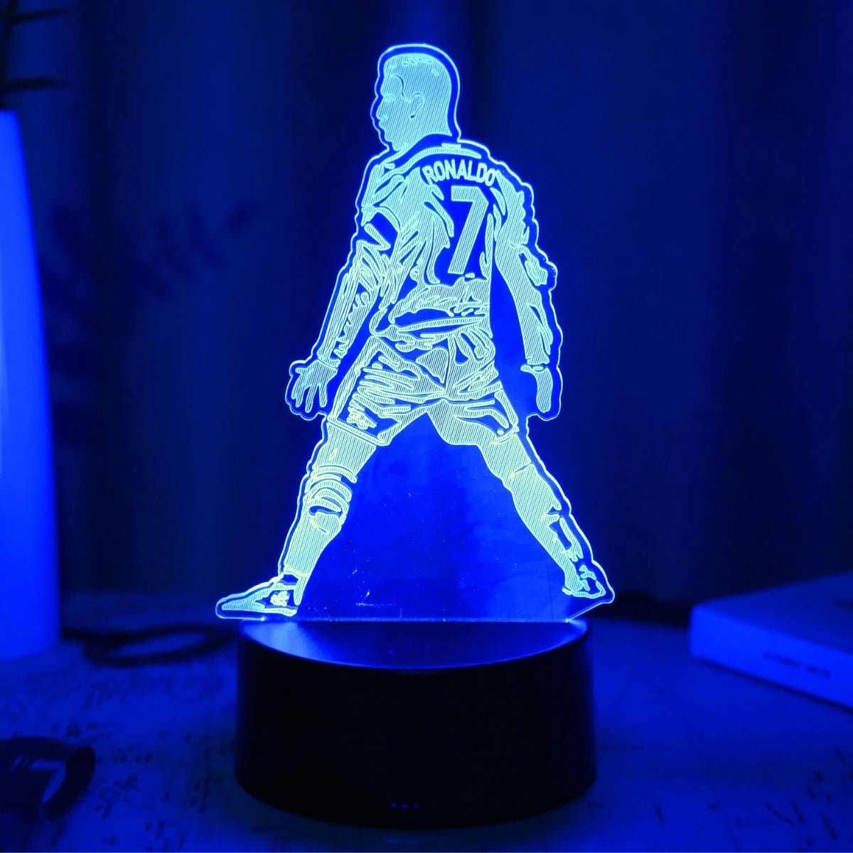 A glowing blue silhouette of Cristiano Ronaldo in a sports uniform displayed on a black base.