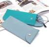 A teal PU leather eyewear case and glasses bag lying next to a pair of eyeglasses on a white background.