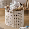 A white folding hand-held clothes storage basket filled with soft stuffed toys.