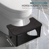 A dark wood horse bucket stool placed next to a white toilet bowl, showing its size and ergonomic design.
