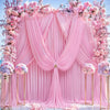 Fondo de tela rosa decorado con arreglos florales y cortinas drapeadas para un evento.