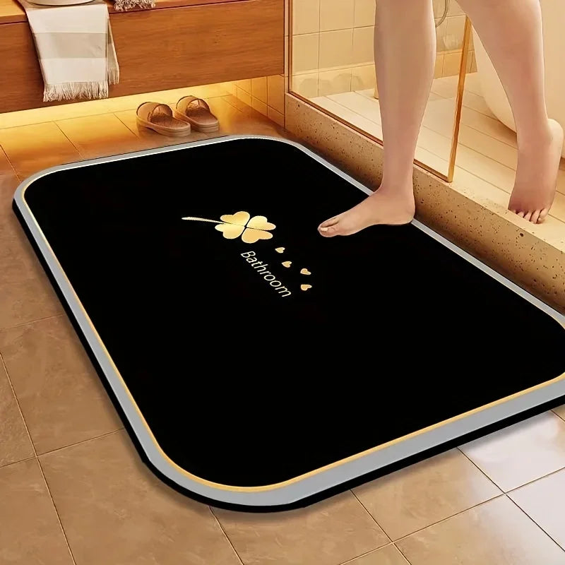 A black quick dry diatomite bath mat with a yellow flower and heart design placed on a tiled floor.